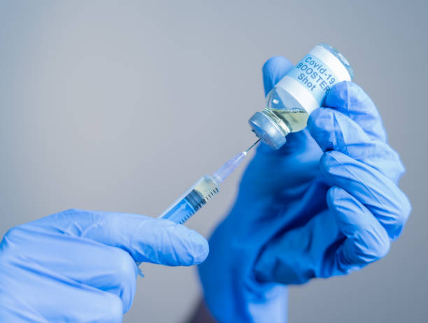 Focus on syringe, close up of doctor or nurse hands taking covid vaccination booster shot or 3rd dose from syringe Focus on syringe, close up of doctor or nurse hands taking covid vaccination booster shot or 3rd dose from syringe. booster dose stock pictures, royalty-free photos & images