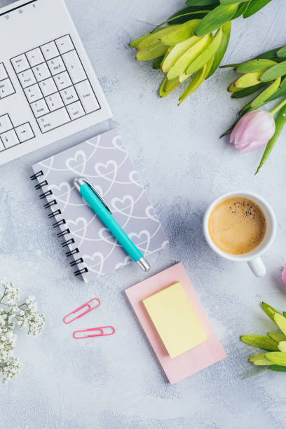 istock Workplace with cup of coffee, empty notebook, keyboard, supplies and flowers 1336121786