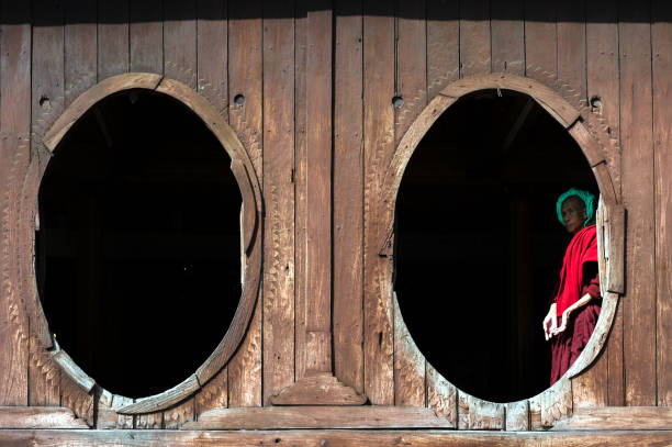 A girl in a traditional ao dai is praying in a temple surrounded by many bright candles. Row of stone turtles in Temple of Literature or Van Thanh temple in Hue city, Vietnam