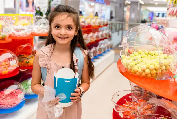 little girl eating chocolate in a candy store