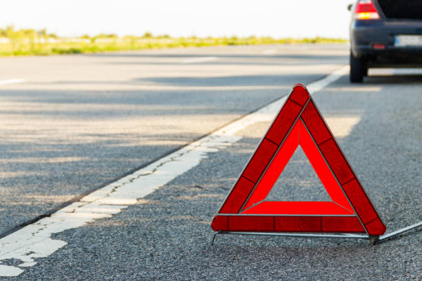 Red emergency stop sign (red triangle warning sign) and broken car on road stock photo