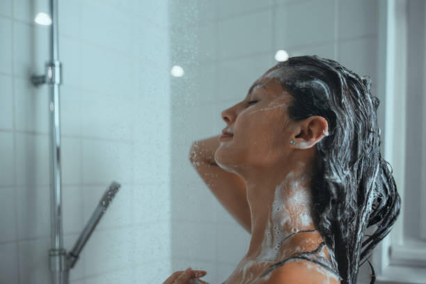 mujer tomando una ducha y lavándose el pelo en casa - bathtub women naked human face fotografías e imágenes de stock