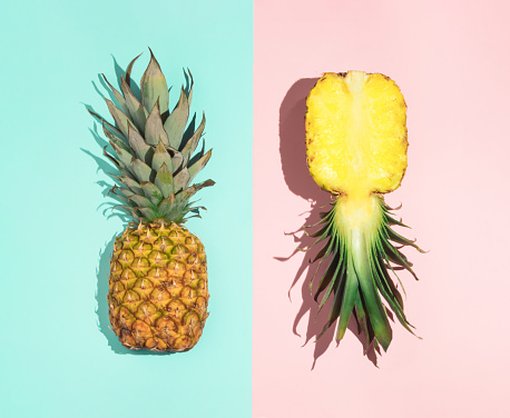Colorful pattern of pineapple on pastel blue and pink background. Top view. Minimal tropical fruit summer concept.