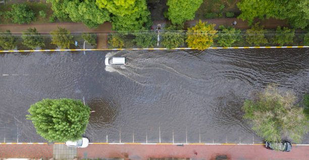 異常な土砂降りの後、車は大洪水の通りで移動しています。 - hurricane lamp ストックフォトと画像