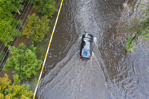 Flooded street after an abnormal downpour in the suburbs. Cars move on the flooded street. Consequences of a natural disaster.