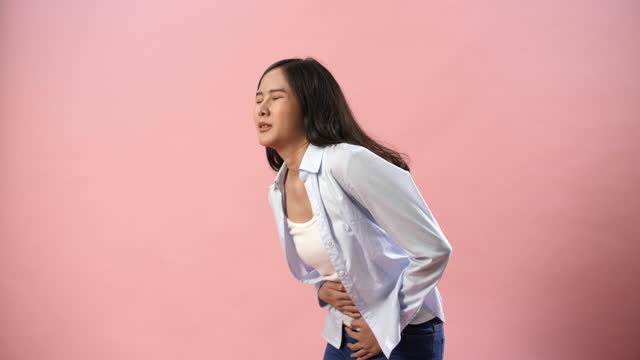 Young woman feel stomachache in  isolated  pink background