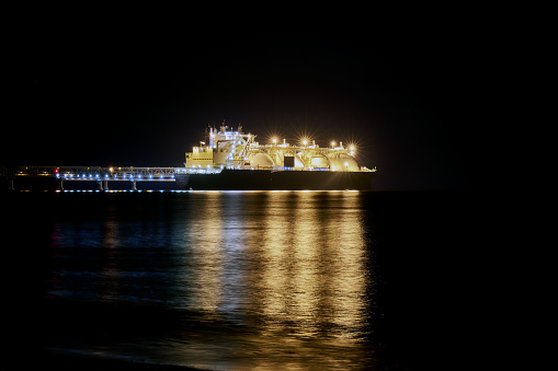 A gas carrier at night against the background of dark sea and an LNG shipment berth. Ocean background.