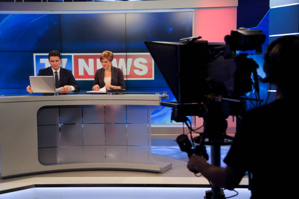 Two commentators preparing for a live interview on the news. Two people in a tv studio talking about the script for the news show.