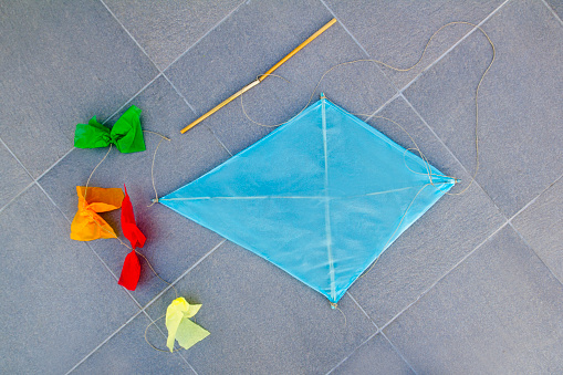 blue children kite traditional diamond shape on gray floor