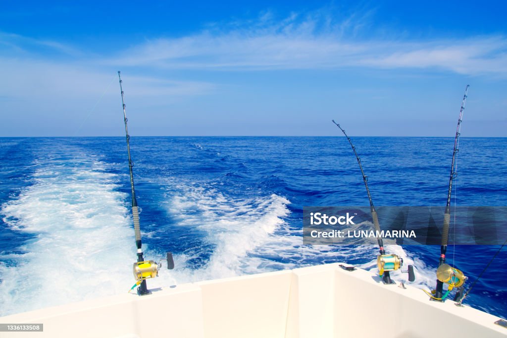boat fishing trolling in deep blue sea boat fishing trolling in deep blue sea with rods and reels Fishing Stock Photo