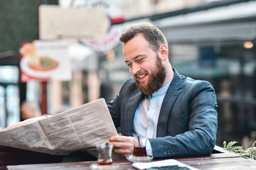 Handsome Businessman Smiling While Drinking Tea And Reading Newspaper