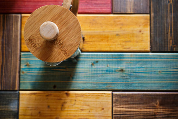 French press coffee maker made of wooden material and colorful wooden background and caffe standing on wooden table.