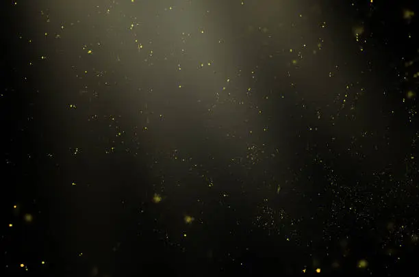 Photo of golden particles in the rays of light on a black background for use with the screen overlay mode