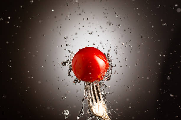 Cherry tomatoes in splashes of water. Black white background