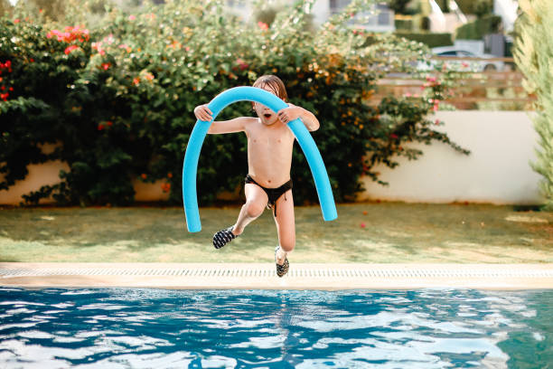 istock The little boy jumps into blue water 1336138812