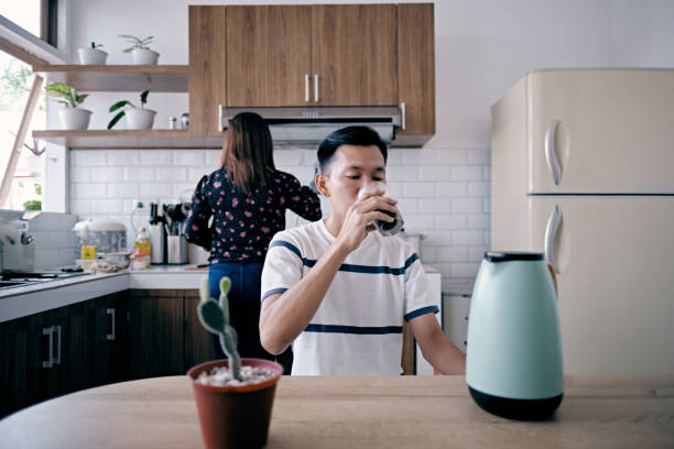 istock Young Man Having a Coffee while His Wife Preparing Breakfast 1336139628