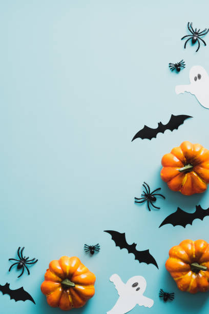 Happy halloween holiday concept. Frame of halloween decorations, bats, ghosts, pumpkins, spiders on blue background. Halloween party invitation card mockup with copy space. Flat lay, top view. feliz concepto de vacaciones de halloween. marco de decoraciones de halloween, murciélagos, fantasmas, calabazas, arañas sobre fondo azul. maqueta de tarjeta de invitación a fiestas de halloween con espacio de copia. lay plana, vista superior.