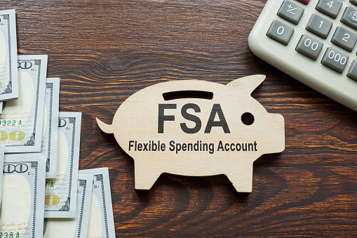FSA flexible spending account words on the wooden piggy bank.