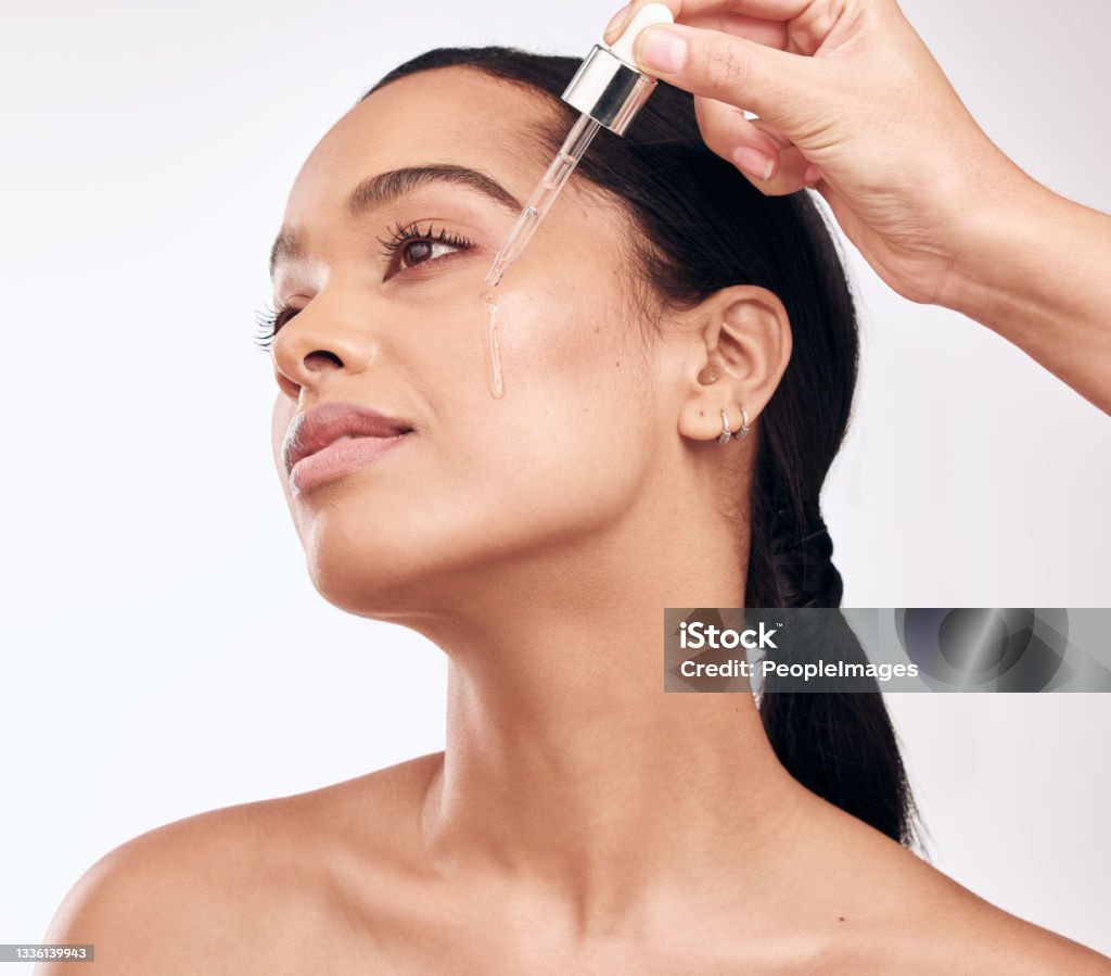 Shot of a beautiful young woman posing with a serum dropper against her face This serum delivers amazing results for your skin Face Serum Stock Photo