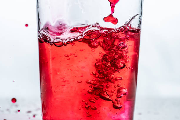 istock Red liquid being poured into a glass. White background... 1336140337