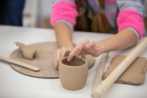 Clay modeling workshop. Hands make an earthenware cup.