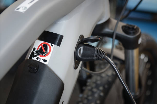 Close up shoto of electric bicycle during charging with charger plugged in Ebike maintenance and charging electric bicycle stock pictures, royalty-free photos & images