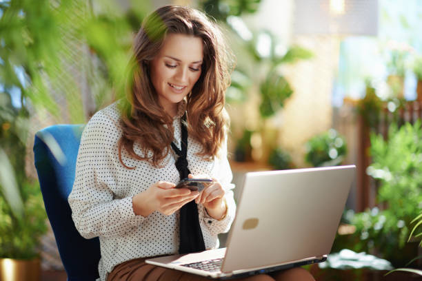 istock smiling elegant woman at home in sunny day using laptop 1336152042