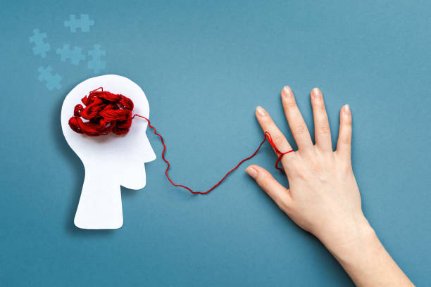 istock Silhouette of a paper human head with tangled red threads instead of brains. A red thread is tied to the index finger of a female's hand. Flat lay. The concept of World Alzheimer's Day 1336153229