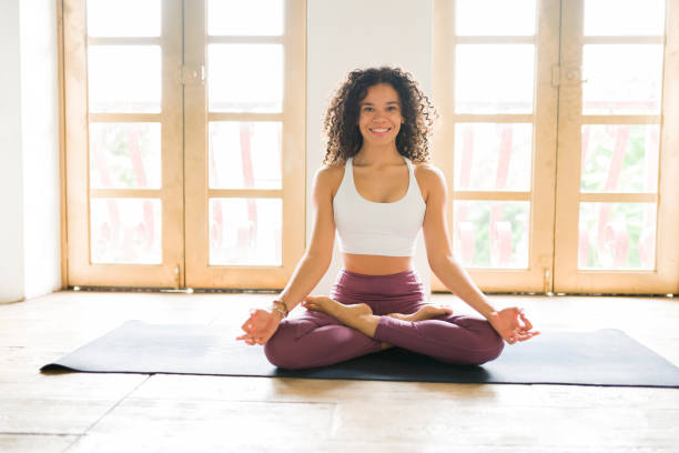 Portrait of a yogi doing breathing exercises I love meditating. Attractive woman in a lotus pose smiling and preparing to do a meditation routine to relax yoga instructor stock pictures, royalty-free photos & images