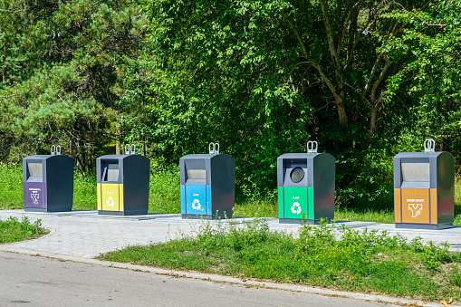 five different waste sorting containers on a city street