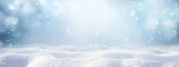 Photo of Winter snow background with snowdrifts, with beautiful light and snow flakes on the blue sky.