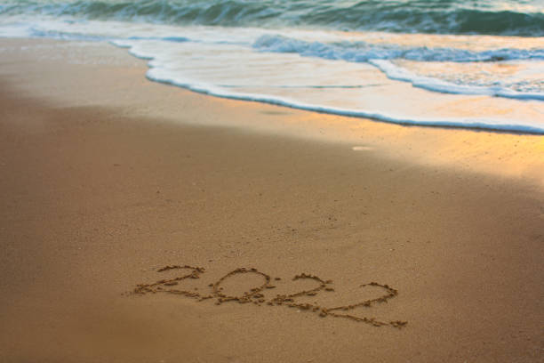 2022 Happy New Year inscription sand beach. stock photo