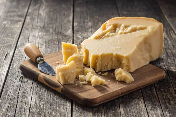 Pieces of italian parmesan cheese. Block of parmesan on wooden table.