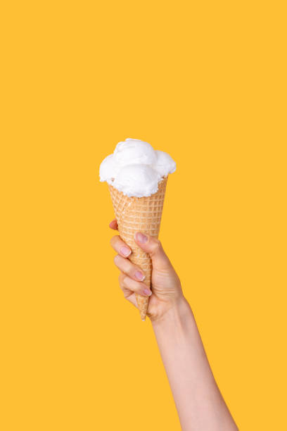 istock Female hand holding waffle cone with scoopes oof vanilla ice-cream 1336160345
