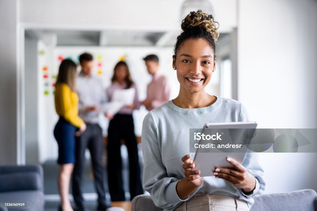 Business woman working online at the office using a tablet Portrait of an African American business woman working online at the office using a tablet computer Marketing Stock Photo