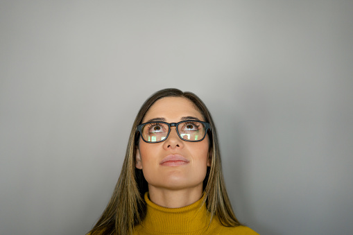 Portrait of a thoughtful business woman looking up while wearing glasses - studio shot concepts