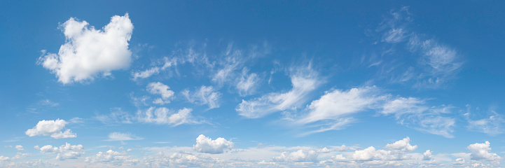White clouds in a blue sky in summer. Panoramic skyscape in 1:3 format.