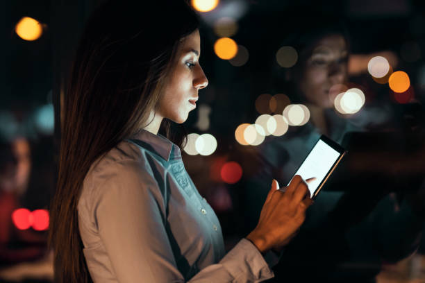 istock Smart pretty business woman taking a break while cheaking her digital tablet standing in the office at night. 1336167015