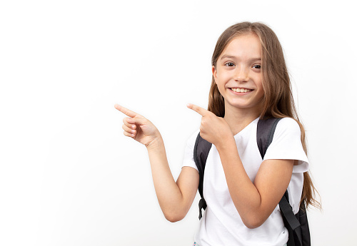 little schoolgirl with schoolbag pointing at empty copy space. education concept, banner, poster.