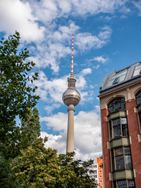 fernsehturm (tour de télévision) à berlin entre l’arbre et une maison. ciel bleu avec quelques nuages. - sky tree audio photos et images de collection