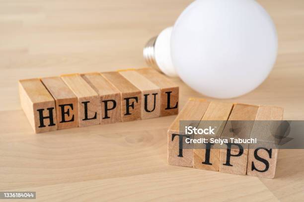 Helpful Tips Wooden Stamps With Helpful Tips Text Of Concept And A Light Bulb On The Table Stock Photo - Download Image Now