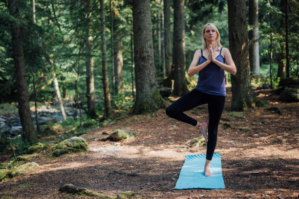 une femme faisant une pose d’arbre de yoga dans les bois - tree stream forest woods photos et images de collection
