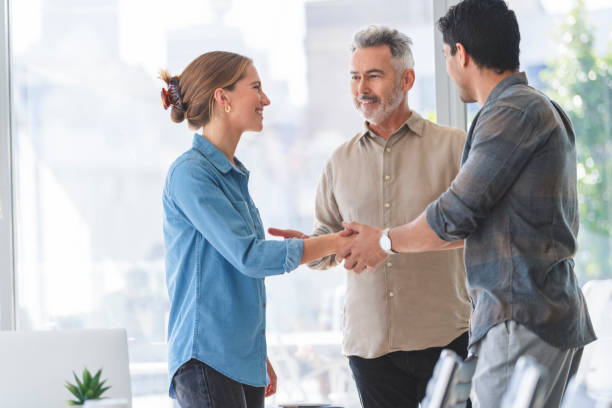 istock Woman and man shaking hands with a mature man congratulating them. 1336187411