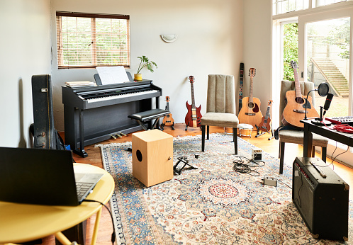 Assortment of guitars, a piano and other musical instruments sitting in a the private recording studio of a home