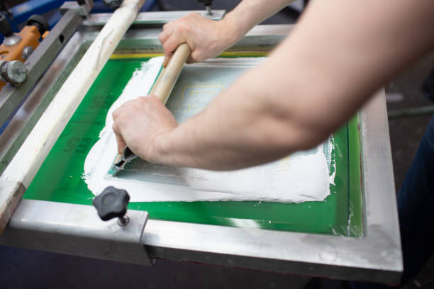 istock Serigraphy silk screen print process at clothes factory. Frame, squeegee and plastisol color paints 1336192117