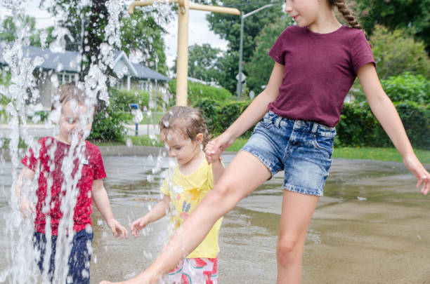istock Two girls and boy playing in water game 1336192608