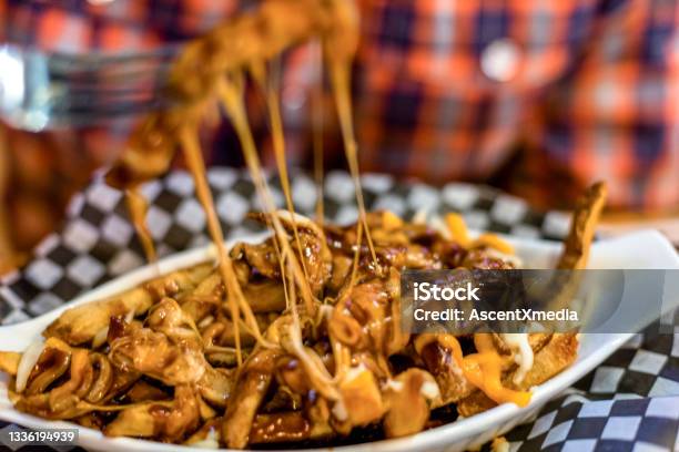 Young Man Enjoys Poutine Meal At Restaurant Stock Photo - Download Image Now - Poutine, Cheese, French Fries