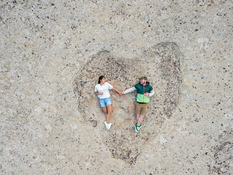 Young Couple Holding Hands on a Heart Shaped Rock