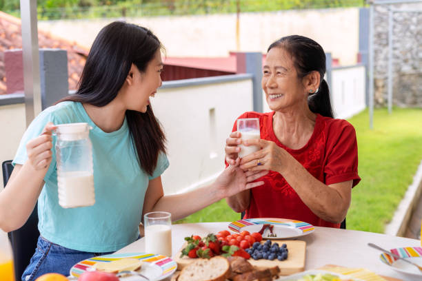 istock daughter drinking milk with senior mother during breakfast 1336205526