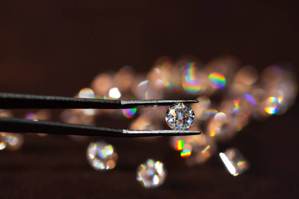 istock Diamond in tweezers on a dark background with diamonds group soft focusing 1336210894